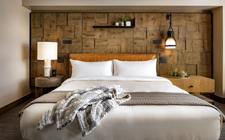 1 hotel sf guestroom king sized bed with a headboard wall that is paneled with end cut woods of multiple species including oak and walnut
