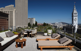 1 hotel sf outdoor terrace from the suite room featuring lounge chairs, tables and a view of the north bay