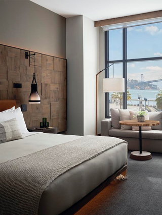1 hotel sf suite with a king bed, a beige sofa and a panoramic view of the bay