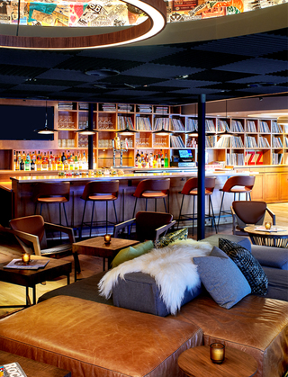 hotel ziggy bar with leather couches and fur throw in the foreground and bar in the background