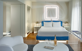 the mondrian guestroom bed with a black rectangular light hung up on a swirl designed wallpaper