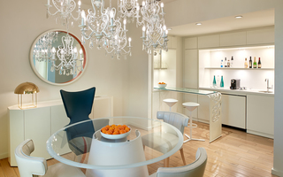 the mondrian round glass dining table and crystal chandelier with the mini bar in the back