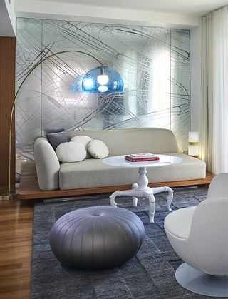 the mondrian guestroom living room featuring a clear blue glass dome floor lamp standing above a beige sofa against the glass decorated wall