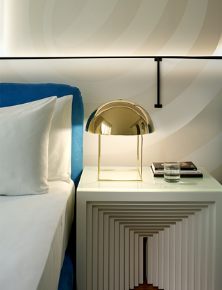 the mondrian bed stand with a gold dome shaped table lamp