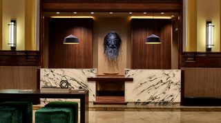 union station nashville wood and granite front desk with a metal wire installation on the wall of a grizzly looking guy wearing glasses