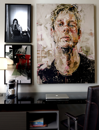 union station nashville guestroom desk with a portrait of a man hanging on the wall, to the left is a smaller image of a man sitting on the floor while playing a harmonica and below that is a framed collage of a train