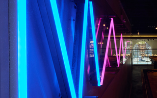 hotel zetta half pink and blue scribbly neon sign hanging in the upstair's game room