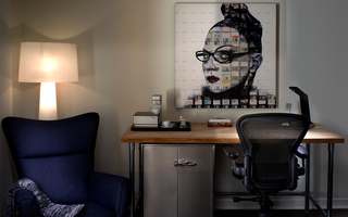 hotel zetta guestroom desk featuring a painting hung on the wall of a woman with glasses and her hair tied up in a bun