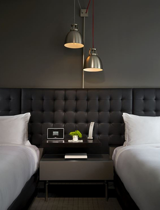 hotel zetta suite featuring a nightstand and twin beds to the left and right of it