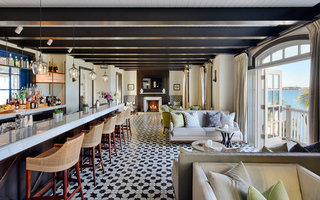 rosewood bermuda conservatory bar with sequenced tile floors, a long spacious bar to the left, a fireplace mantal and tv on the backwall, and ample seating and chairs to the right