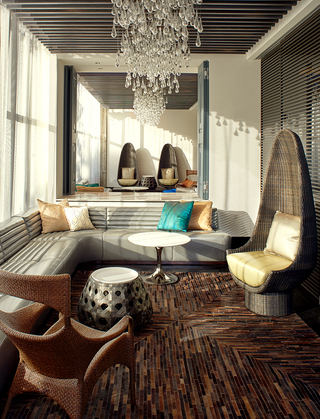 w la lobby lounge featuring woven ratten chairs and a grey sofa with a teardrop chandelier hanging above