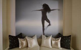 w la beige sofa and decorative pillows up against a mural on the wall of a ballet dancer posing in a blue-grey fog background