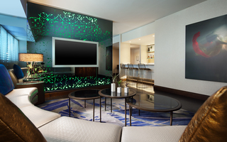 w la suite living room with a tv mounted on a green decorated mirror wall and adjacent lies a cream-colored leather sofa and mural hung on the wall of a mermaid twirling in a body of water