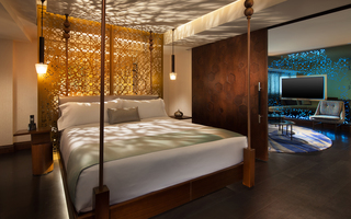 w la suite bedroom featuring a king-sized bed up against a decorative wood panel with light reflecting off of it