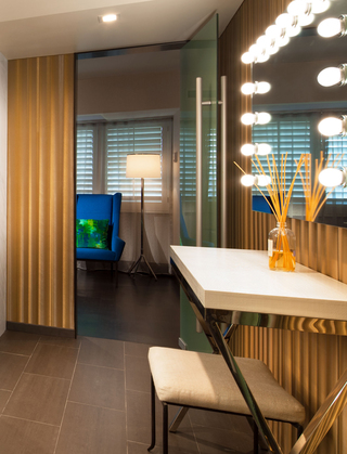 w la suite bathroom featuring a Hollywood makeup mirror, white vanity desk, and bench