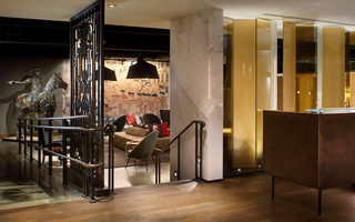 revere hotel reception desk next to a small flight of stairs leading down to the bar seating area and the metal statue of Paul Revere