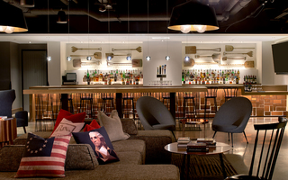 revere hotel bar including chairs and a US 13-star flag pillow, a George Washington pillow, and 'join or die' snake pillow on the grey sofa