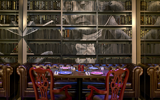 revere hotel rebel's guild dining area and on the wall is a bookshelf filled with books. Painted across the row of books is a mural of John Adams in black and white