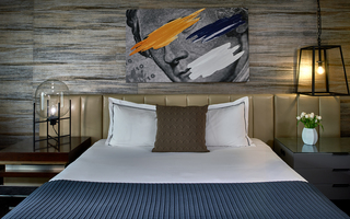 revere hotel guestroom king bed and hanging on the wall above the bed is a mural of George Washington with orange, blue and white paint streaks going across his face