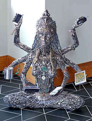 hotel zelos woman sculpture by Brian Mock holding various items like a broken IPhone, computer mouse, metal cup, calculator etc.