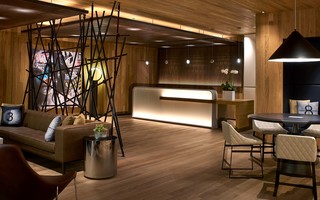 hotel palomar la reception desk and parallel to the desk is a black metal rod light installation behind the leather sofa