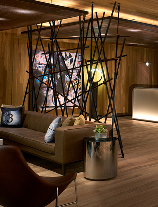 hotel palomar la close up of the black metal rod light installation and in the background a mural of a woman with poster clippings overlap her face