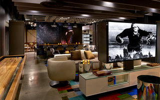 hotel palomar la lounge featuring armchairs and sofas surrounded by board games, a shuffleboard table, TVs, and an image on the wall of a gorilla roaring in the back