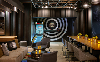 hotel palomar game room with a skee-ball machine in front of a bullseye painted wall and, in the center, hangs a dart game