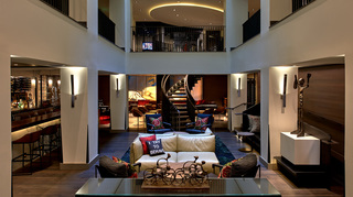 hotel vintage portland lobby bar to the left and lounge chairs and loveseats at center leading up to the winding staircase