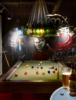 hotel vintage portland second floor pool table with a glass bottle chandelier hanging from the ceiling above and graffiti decorated on the black walls in the background