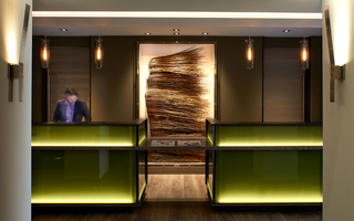 hotel vintage portland green glass reception desk and on the back wall is a wooden sculpture displayed in a glass case