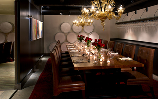 hotel vintage portland two golden glass chandeliers hanging above a long wooden dining table and brown leather chairs in the dining room