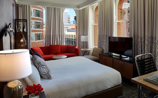 hotel vintage portland suite with 1 king bed, a tv, red sofa, and a window view of the city