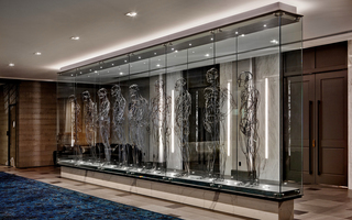 the logan nine metal wire statues lined up in a row inside of a long glass light display in the lobby