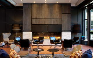 the logan large industrial fireplace at the back wall of the lobby facing the chairs and tables in the lounge