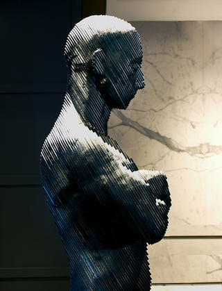 the logan close up of the life size metal statue of a man standing with his arms crossed in the lobby