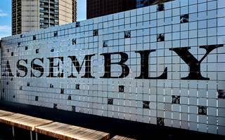 assembly rooftop sign made up of small white square tiles with 'assembly' printed in black across the tiles and scattered across the sign are numerous tiles with selfies of people in black and white