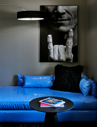 villa florence guestroom blue patent leather couch and a black and white photograph of a man holding up a rock and roll hand sign on the wall