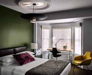 hotel zeppelin guestroom bed and desk with a hanging light fixture reflecting a peace sign on the ceiling