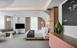 hotel zena bedroom in the suite featuring a butterfly mural running up from the bed headboard to the ceiling. To the right, hangs a mural of a woman posing in the dark and sitting below that on top of a dresser is a leaf vase sculpted in the shape of a woman's hips