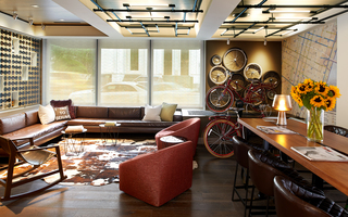 hotel vintage portland lobby lounge featuring bicycle wheels decorated on the right side of the wall, an elaborate wine glass display to the left, and furniture on a white a brown cow skin rug in the center