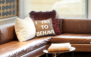 hotel vintage portland lobby lounge close up the leather couch and a pillow with a quote saying "I try to behave"