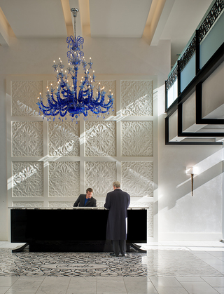 hotel sorella lobby front desk with a blue crystal chandelier hanging from the ceiling