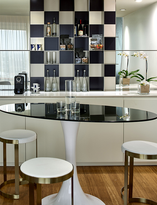 the mondrian mini bar in the suites with a black and white checkered floating wall shelf on the counter and table seating at front
