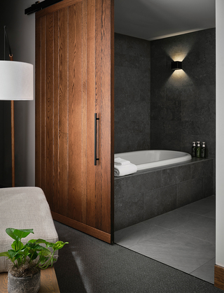 1 hotel sf large sliding wooden bar door leading into the bathroom with a tub