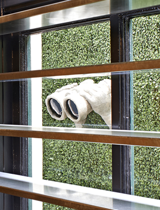 dirty habit sf small clay sculpture of two hands emerging from the outdoor bushes holding binoculars in the direction of the window in to the restaurant